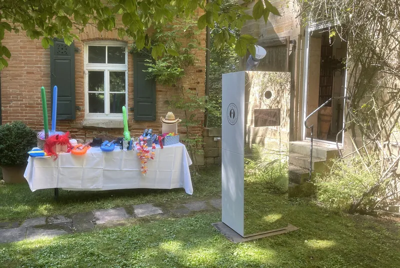 Spiegelfotobox und Tisch mit bunten Requisiten im Garten